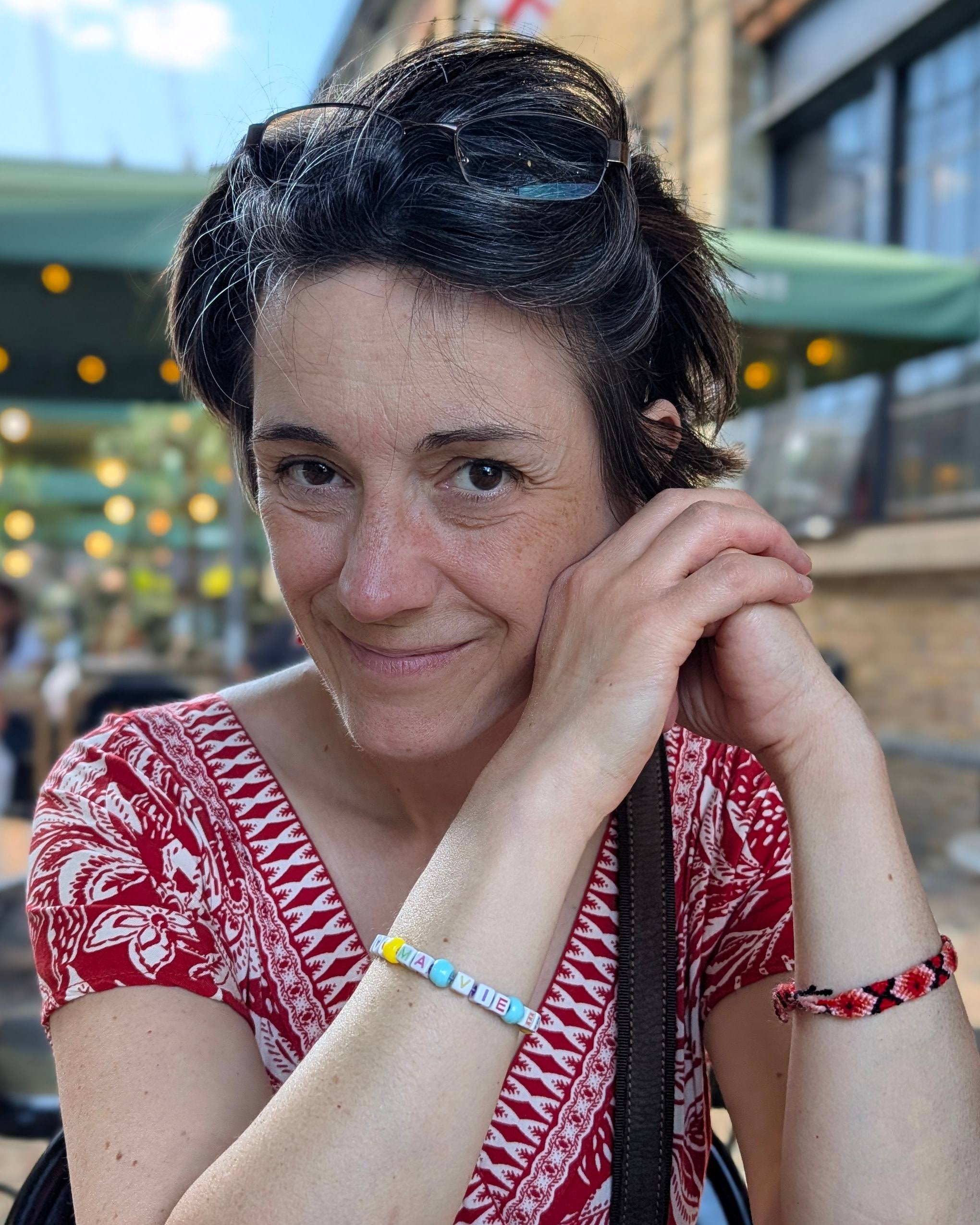Marie Decouvreur sourit, la joue appuyée sur ses mains jointes, accoudée à une table.